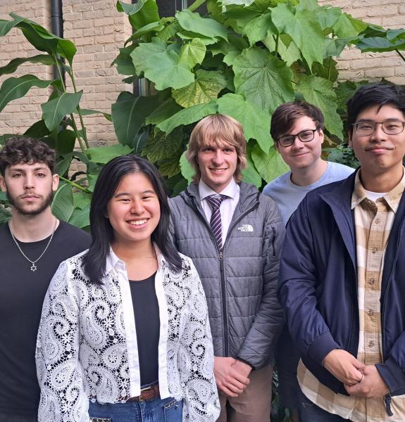 Group of five people in front of large outdoor plant