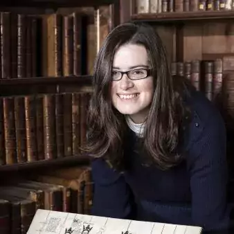 Joanna Bellis headshot in front of bookshelves holding a manuscript